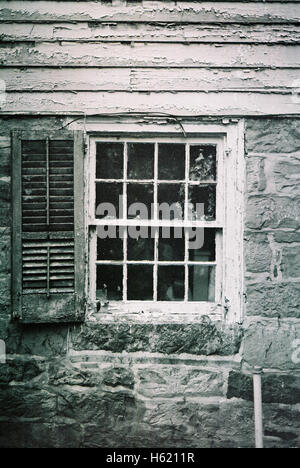 Creepy window with wooden shutters in an abandoned colonial style house in New Jersey USA shot with a Minolta X700 film camera and Kodak BW400 black and white film Stock Photo