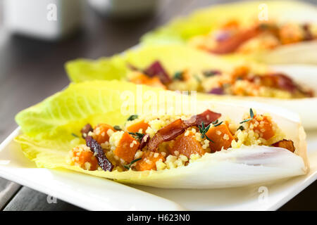 Endive leaves filled with a salad of couscous, pumpkin, red onion and bacon, sprinkled with fresh thyme leaves Stock Photo
