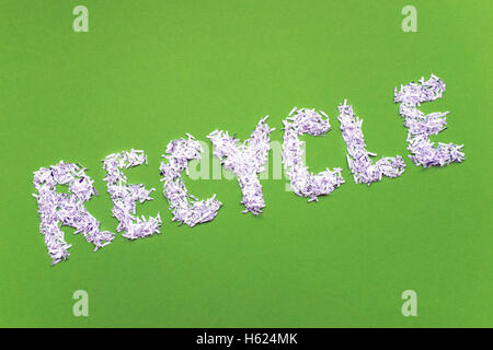 tilted recycle word made from heap of shredded white paper over bright green background Stock Photo