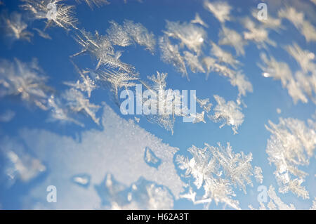 Sparkling snowflakes on a window against the blue sky. Stock Photo