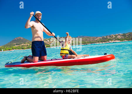 Father with his little happy son having fun on stand up paddle board on Corsica island, France. Stock Photo