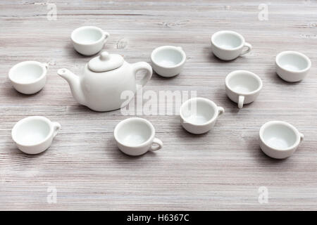 food concept - many white ceramic cups and teapot on gray brown table Stock Photo