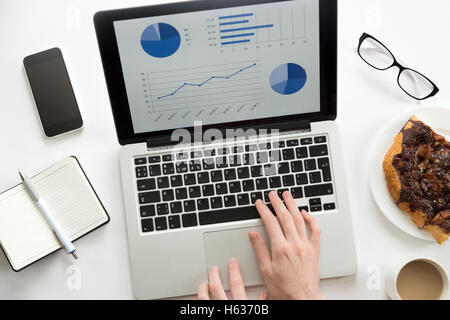 Hands working on a laptop with a diagram on it Stock Photo