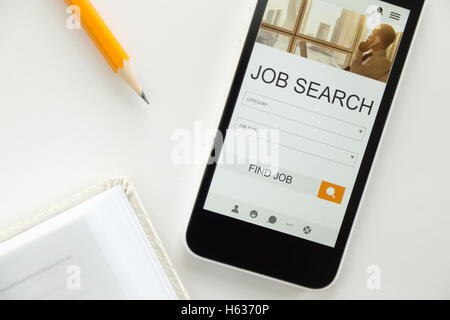 Top view of a mobile phone lying on desk, job search Stock Photo