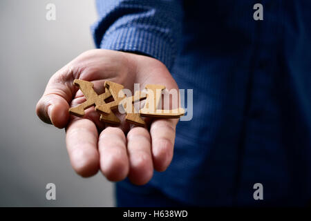 closeup of some wooden letters forming the expression XXL, for extra extra large, in the hand of a young caucasian man Stock Photo