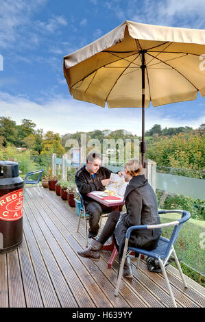 Young couple choose from the menu on the cafe terrace at Kent's Cavern in Torquay Devon Stock Photo