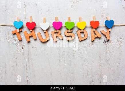word Thursday from wooden letters with colored clothespins on a white wooden background Stock Photo