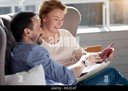 Side view of couple using laptop on couch Stock Photo