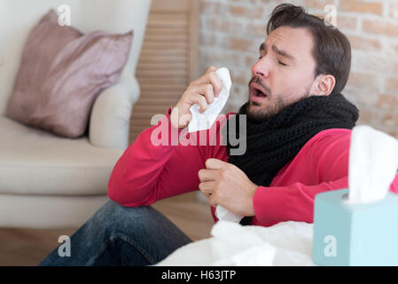 Pale unhappy man sneezing Stock Photo