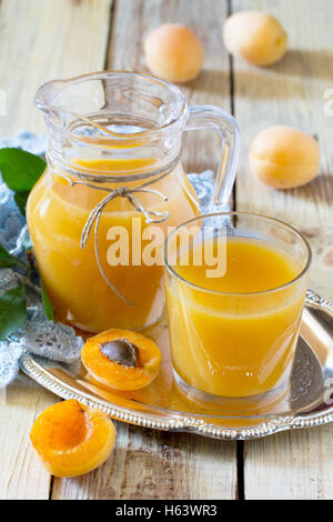 The refreshing summer drink with peach in a jug and glasses on a wooden table Stock Photo