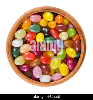Jelly beans in wooden bowl on white background. Assorted small bean-shaped sugar candies in different colors with soft candy. Stock Photo