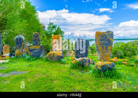 The black khachkars, covered with orange lichen and moss on the medieval cemetery of Hayravank Monastery on bank of Sevan Lake Stock Photo