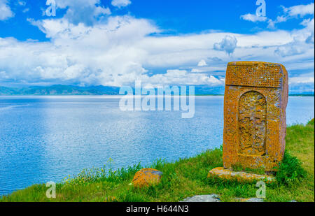 The orange khachkar, covered with lichen, located on the bank of Sevan Lake, on cemetery of Hayravank Monastery, Armenia. Stock Photo