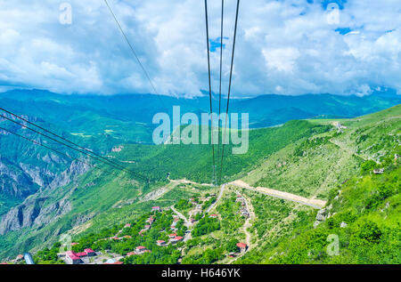 The cables of the longest reversible aerial tramway Wings of Tatev above the Halidzor village with the cloudy mountains around Stock Photo