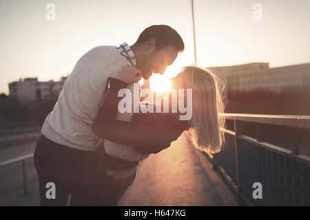 Romantic couple kissing in city during sunset Stock Photo