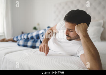Heartbroken lonely man in pajamas on bed Stock Photo