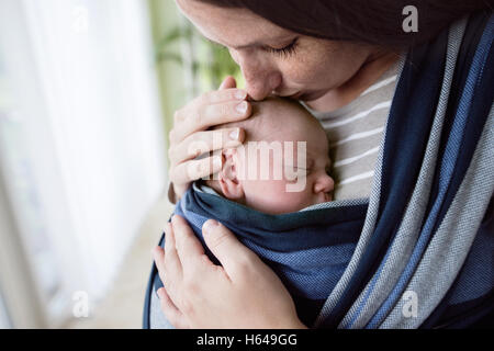 Close up, beautiful mother kissing her son in sling Stock Photo
