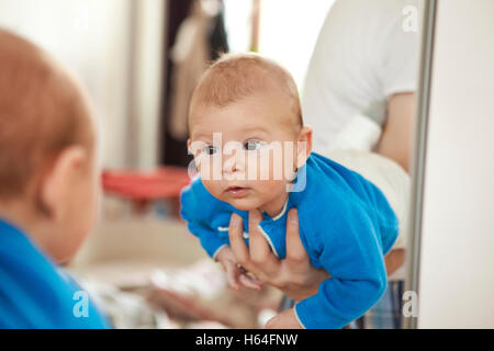 Baby being held to see his own reflection in mirror Stock Photo