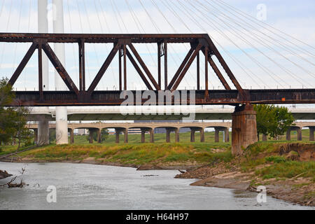 Steel truss railroad, cable automobile, and concrete pedestrian bridge provide access to downtown Dallas over the Trinity River. Stock Photo