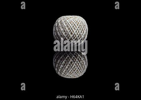 Side view of white ball of string isolated on black reflective background Stock Photo