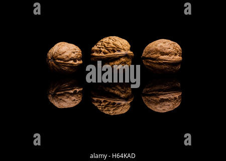 Three whole walnuts isolated on black reflective background Stock Photo