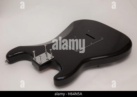 Back of a black fender stratocaster copy electric guitar body, neck removed, with the screws loosened Stock Photo