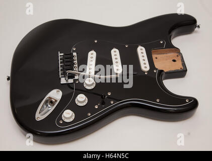 A black fender stratocaster copy electric guitar body, neck removed, tremolo arm attached Stock Photo