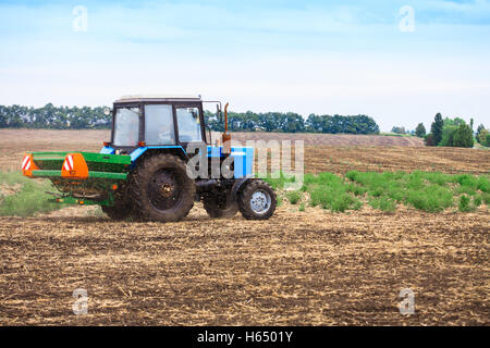 Rural landscape with old tractor in a field sow seed in the plowed soil. Stock Photo