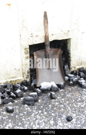 domestic coal bunker with coal coal shovel. Sprinkling of winter snow on ground Stock Photo