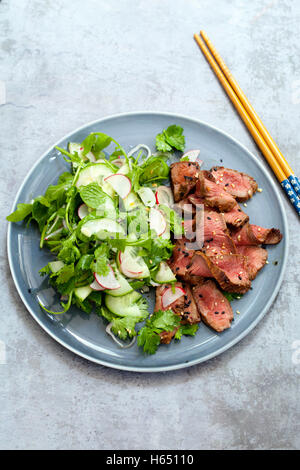 Asian beef salad with cucumber and herb salad and black and white sesame seeds Stock Photo