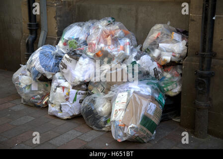 Bags of rubbish in tiled alley near drain pipes Stock Photo