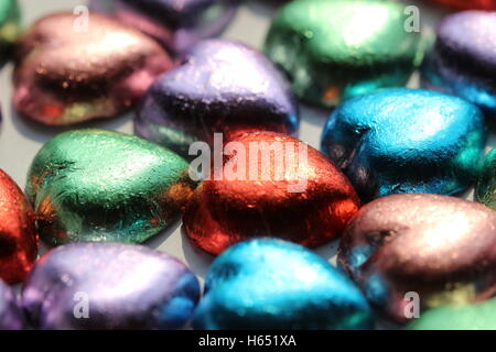 Heart chocolates wrapped in colorful wrappers on a white background Stock Photo