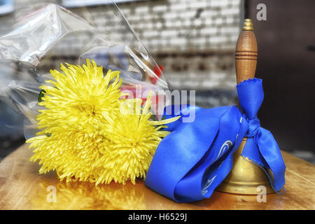 Old school bell with yellow flowers. Last call, graduation. Stock Photo