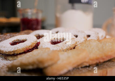 cookies and biscuits presented on a wooden board with ingredients next to it Stock Photo