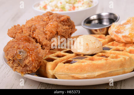 Chicken and waffles served with maple syrup, and orange honey butter Stock Photo