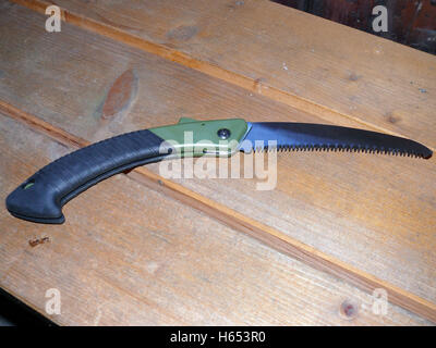 a pruning saw with green handle on wooden background Stock Photo