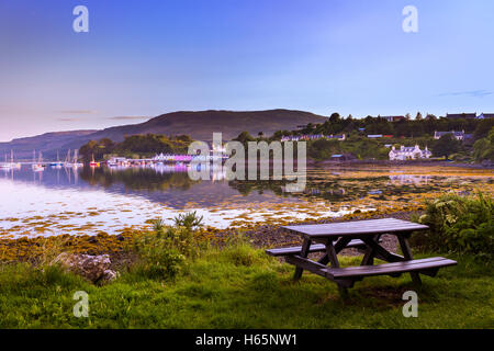 Empty Picnic Table At A Bay During Sunset With View Of Colorful Houses And Sail Boats In The Distance Stock Photo