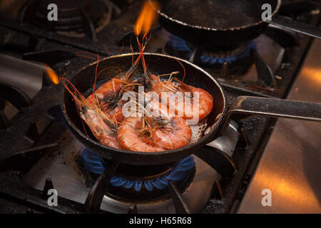 King prawns in the shell cooking on a gas ring, flames from the prawn tail Stock Photo