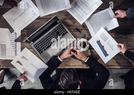 Paperwork and deadline concept - stressed businessman with papers and charts sitting at table in office Stock Photo