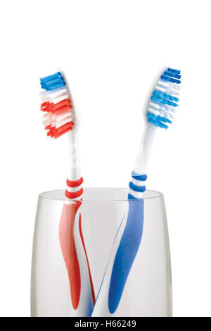 Two toothbrushes in glass, large detailed isolated macro closeup, red, blue toothbrush pair accents Stock Photo
