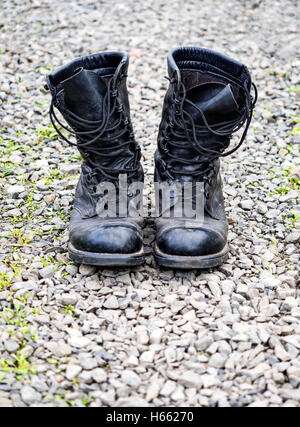 Pair of old black boots on stones surface, shallow depth of field Stock Photo