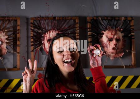 Young strange woman showing peace and holding eyeball in wrinkled hand for concept about Halloween or torture Stock Photo