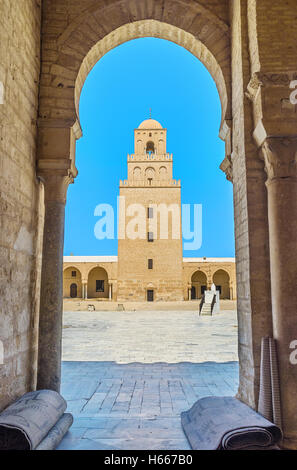 The view on the old Minaret of the Grand Mosque through the arch of its courtyard, Kairouan, Tunisia. Stock Photo