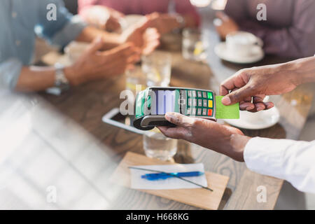 Waiter using credit card reader at restaurant table Stock Photo
