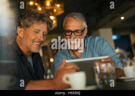 Men using digital tablet at restaurant table Stock Photo