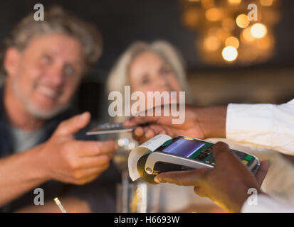 Close up waiter using credit card machine returning credit card to couple Stock Photo