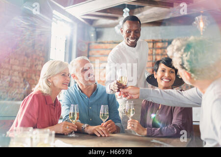 Waiter serving white wine to couples at restaurant table Stock Photo