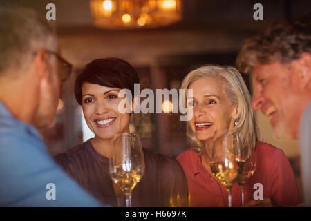 Couples drinking white wine and talking at bar Stock Photo