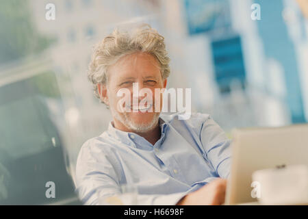 Portrait smiling businessman using digital tablet at sidewalk cafe Stock Photo