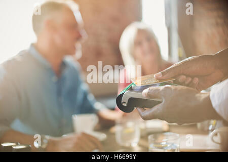 Close up waiter using credit card reader at restaurant table Stock Photo